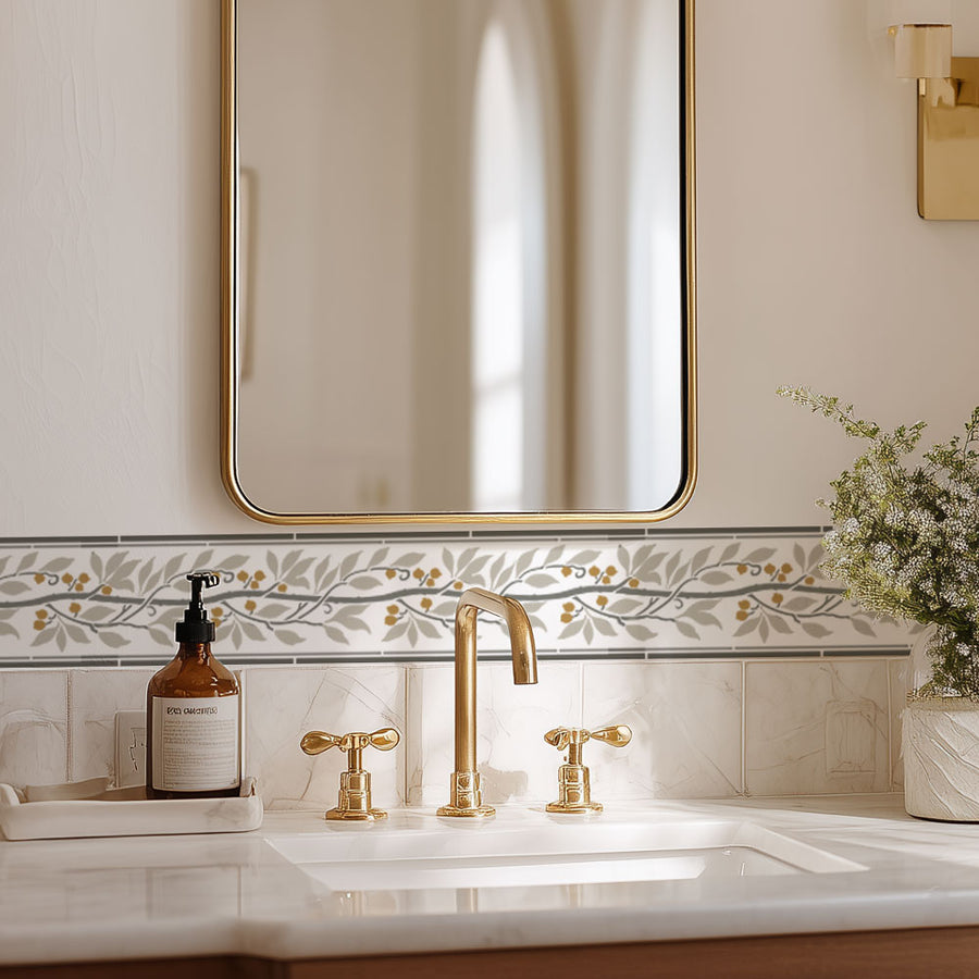 Bathroom sink with gold fixtures, mirror, and decorative stencil border on the wall.
