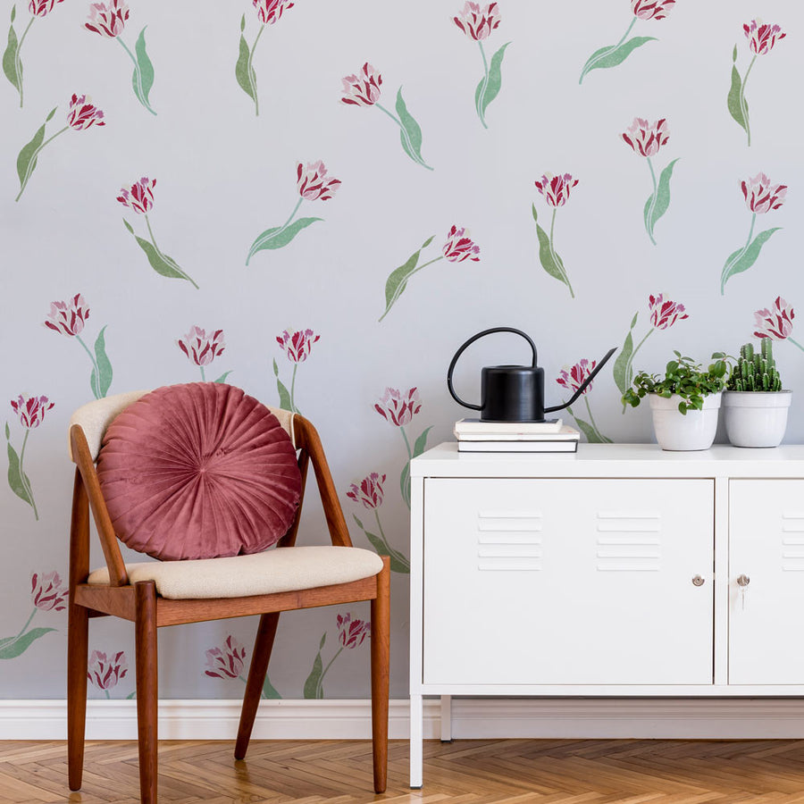 Chair with a pink cushion and a white cabinet against a floral wallpapered wall.