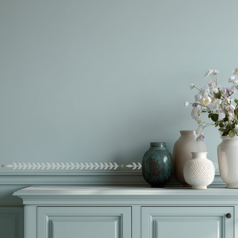 Rosemary stripe stencil border and Decorative vases on a cabinet against a light blue wall 