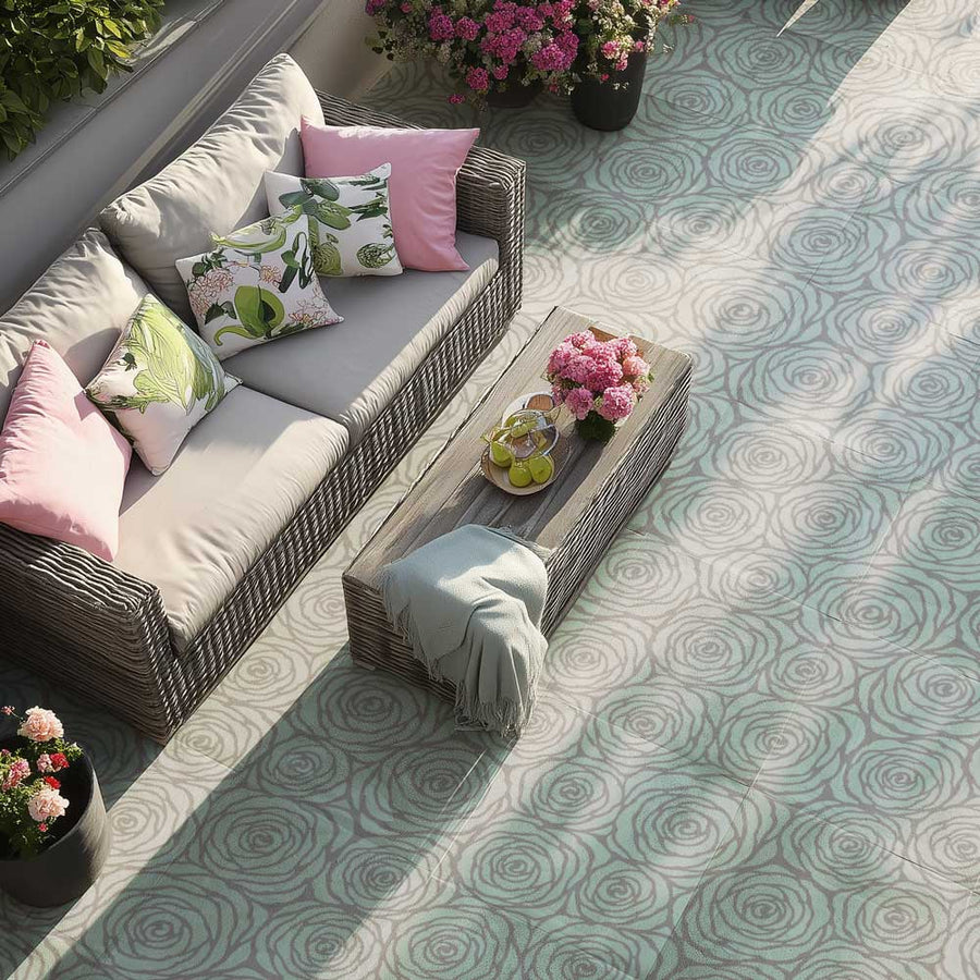 Outdoor concrete patio with wicker furniture, cushions, and flowers on a stenciled floor.