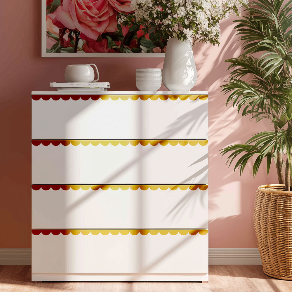 White dresser with colorful trim in a room with a pink wall, plant, and framed artwork.