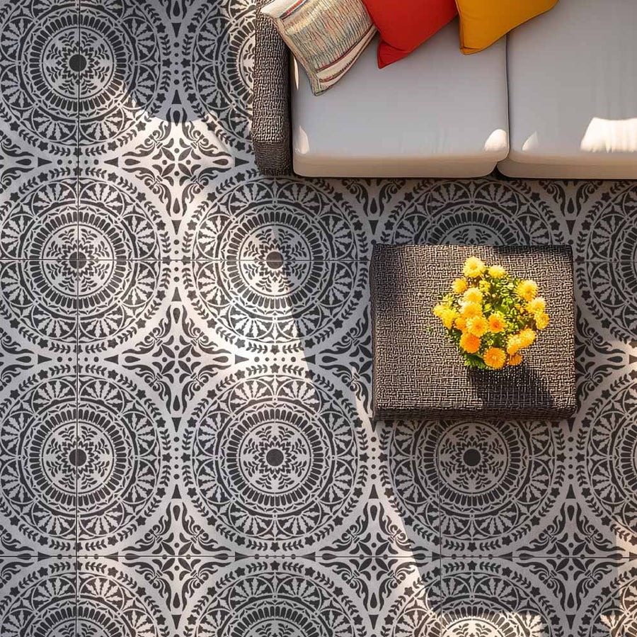 Patterned stenciled floor with a textured rug and colorful pillows on a concrete patio