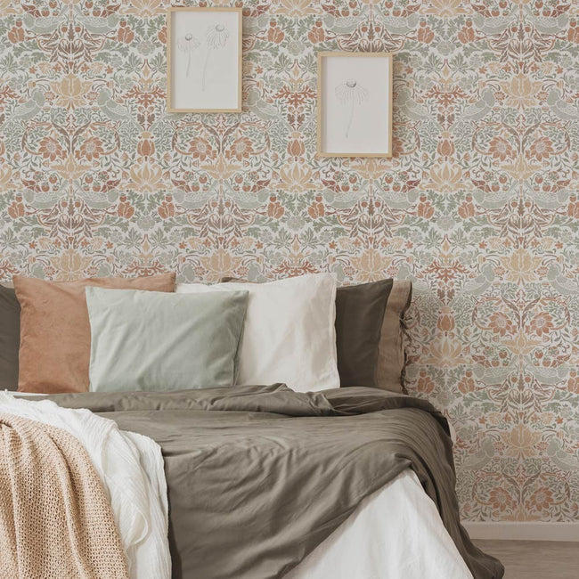 Bedroom with a william morris strawberry thief floral wall stencil, bed with pillows, and framed pictures on the wall.