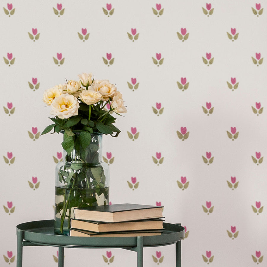 Vase with flowers and books on a table against a floral stenciled wall.