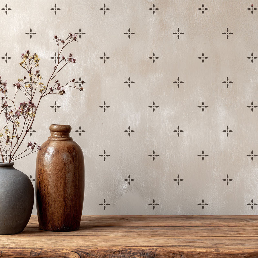 Two vases on a wooden surface with a decorative wall stencil pattern in the background