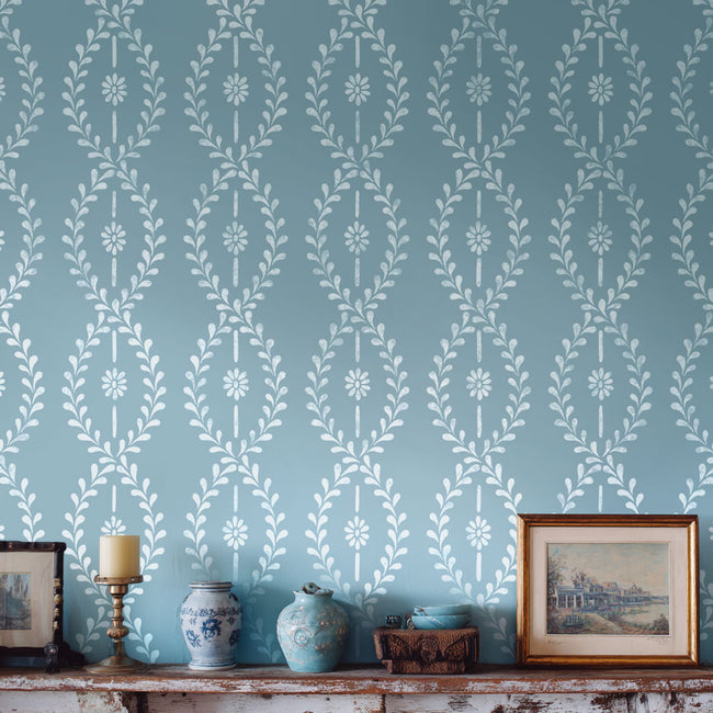 wall stencil design with decorative white stripe stenciled on a blue background, featuring a shelf with decorative vases and frames