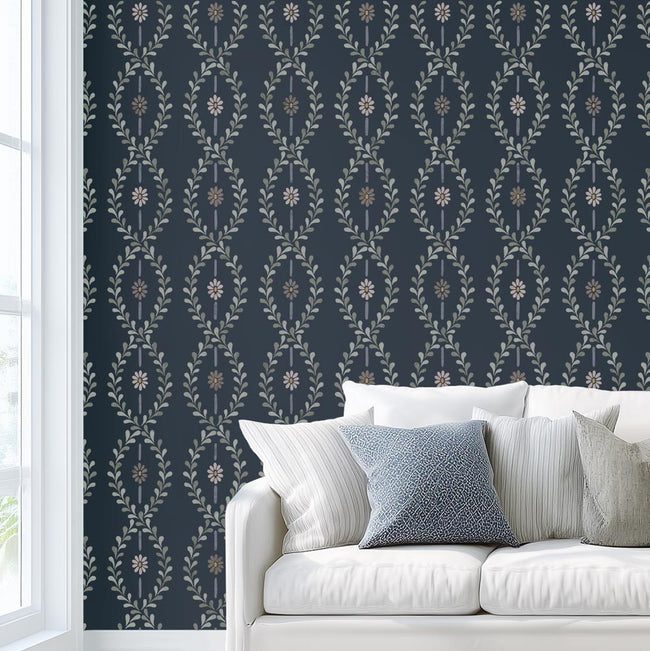 Wall stencil in cottage style next to white sofa with blue and white pillows against a dark blue wall with floral stripe stencil pattern