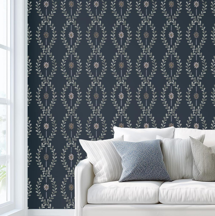 Wall stencil in cottage style next to white sofa with blue and white pillows against a dark blue wall with floral stripe stencil pattern