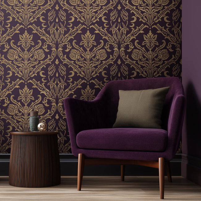 Purple armchair with a pillow against a decorative gold stenciled purple damask wall.