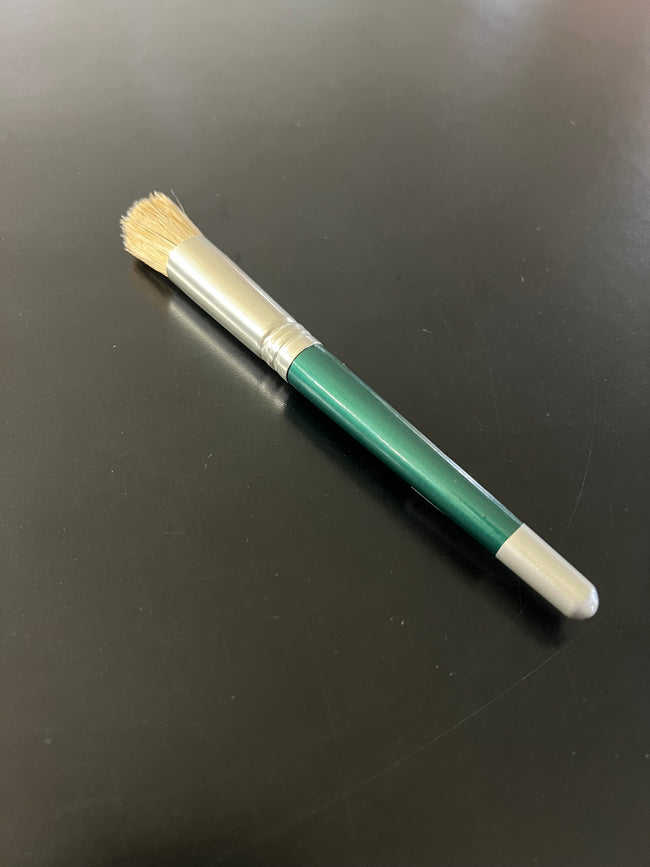 paint brush with green handle and silver ferrule on a black surface