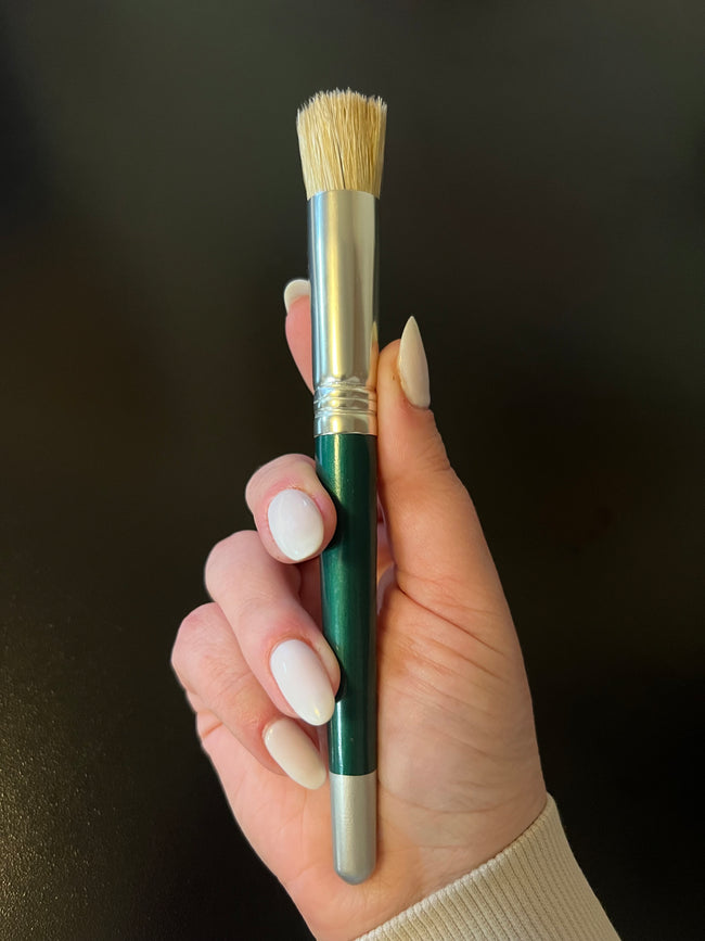 Hand holding a paint brush with a dark background