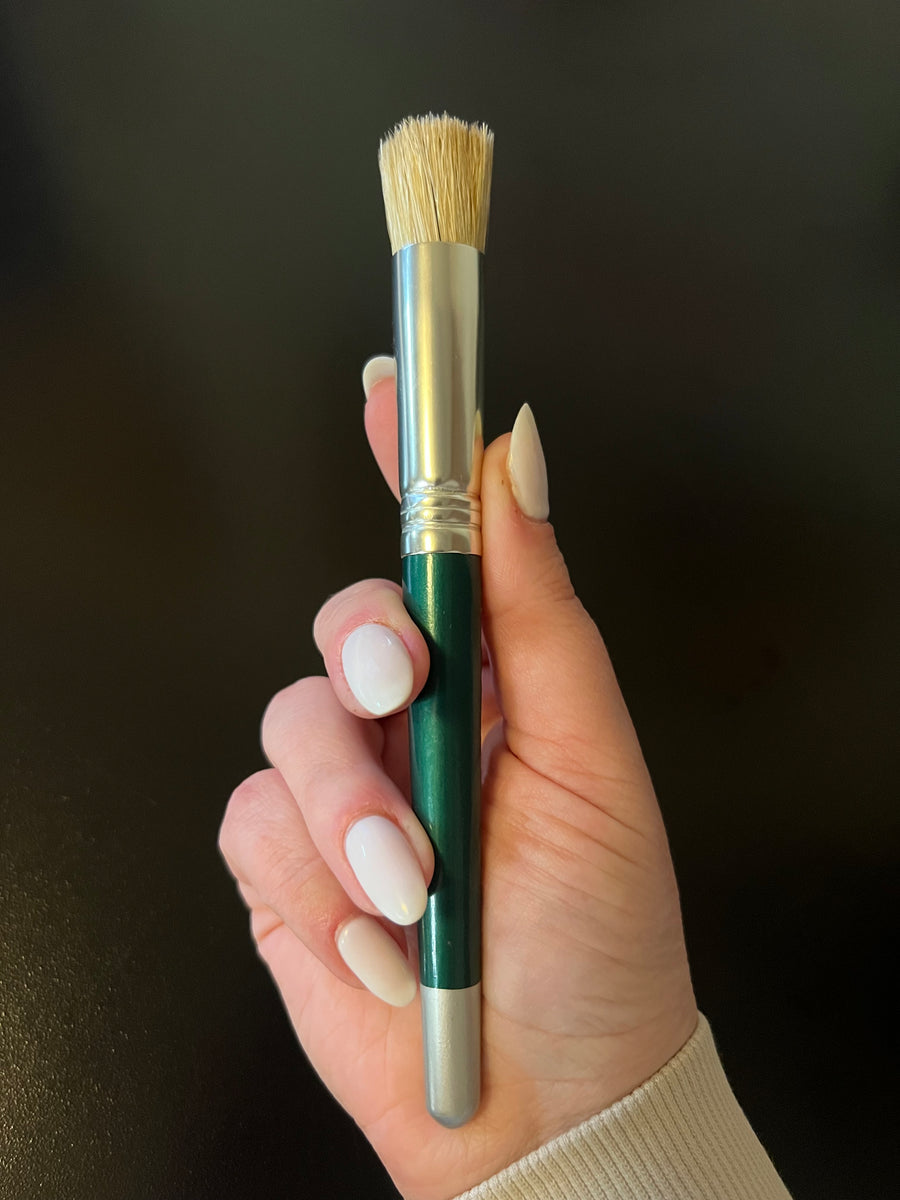 Hand holding a paint brush with a dark background