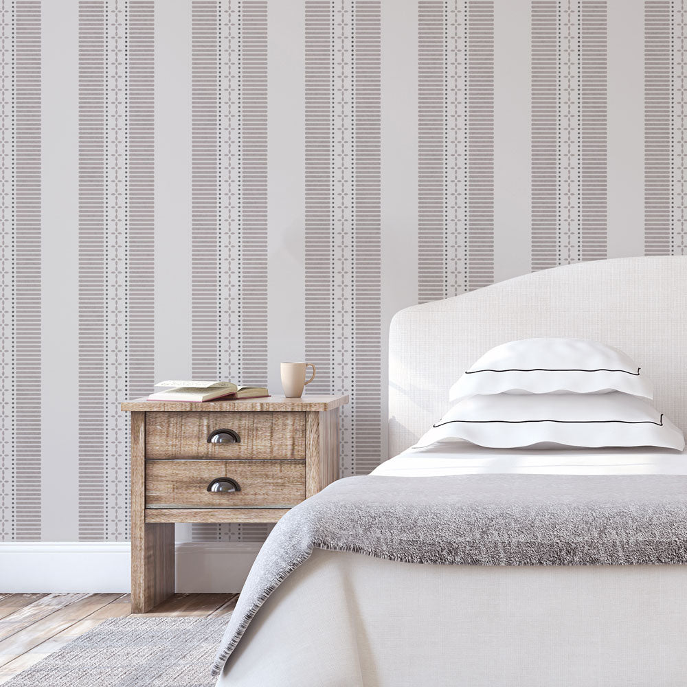 Bedroom with striped wall stencil, wooden nightstand, and bed with white bedding.