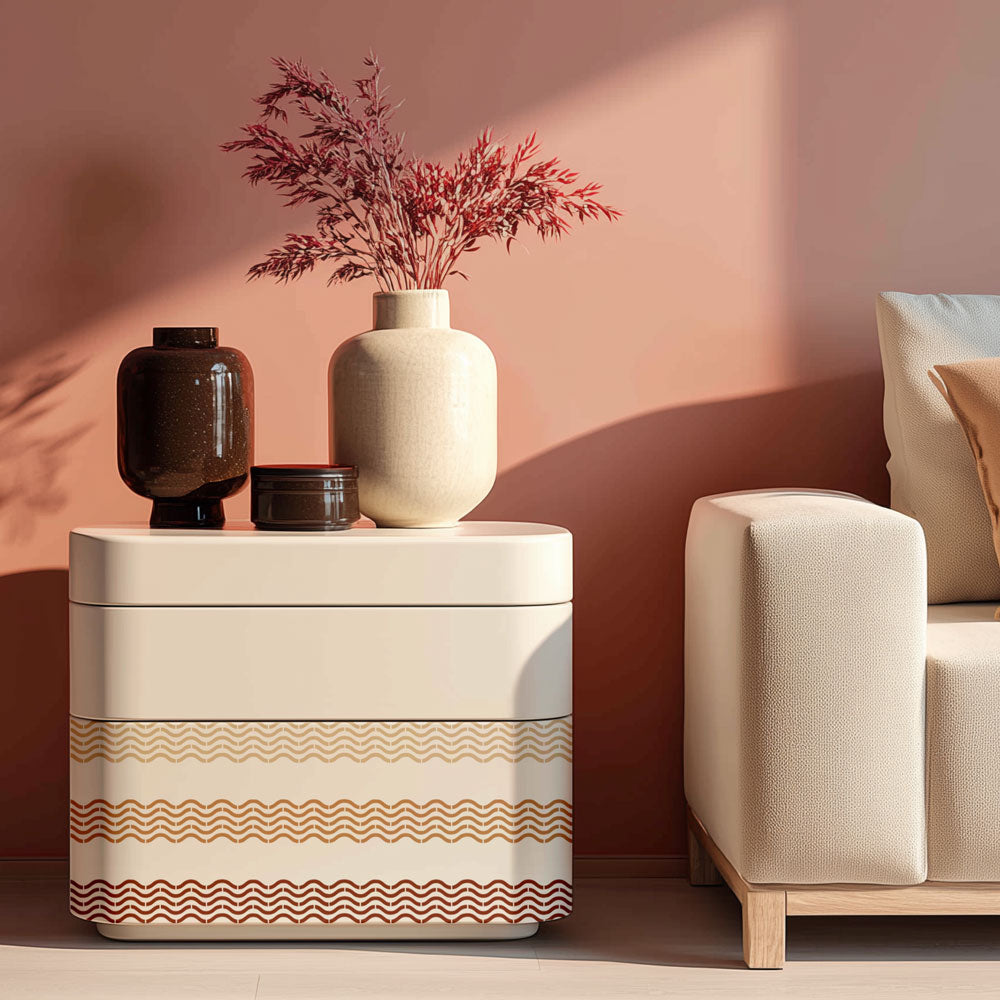 Decorative side table with wavy stencil pattern next to a beige armchair against a pink wall.