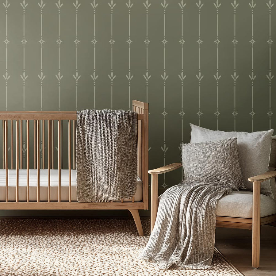 Nursery room with wooden crib and chair against a green wall stencil with decorative pattern.